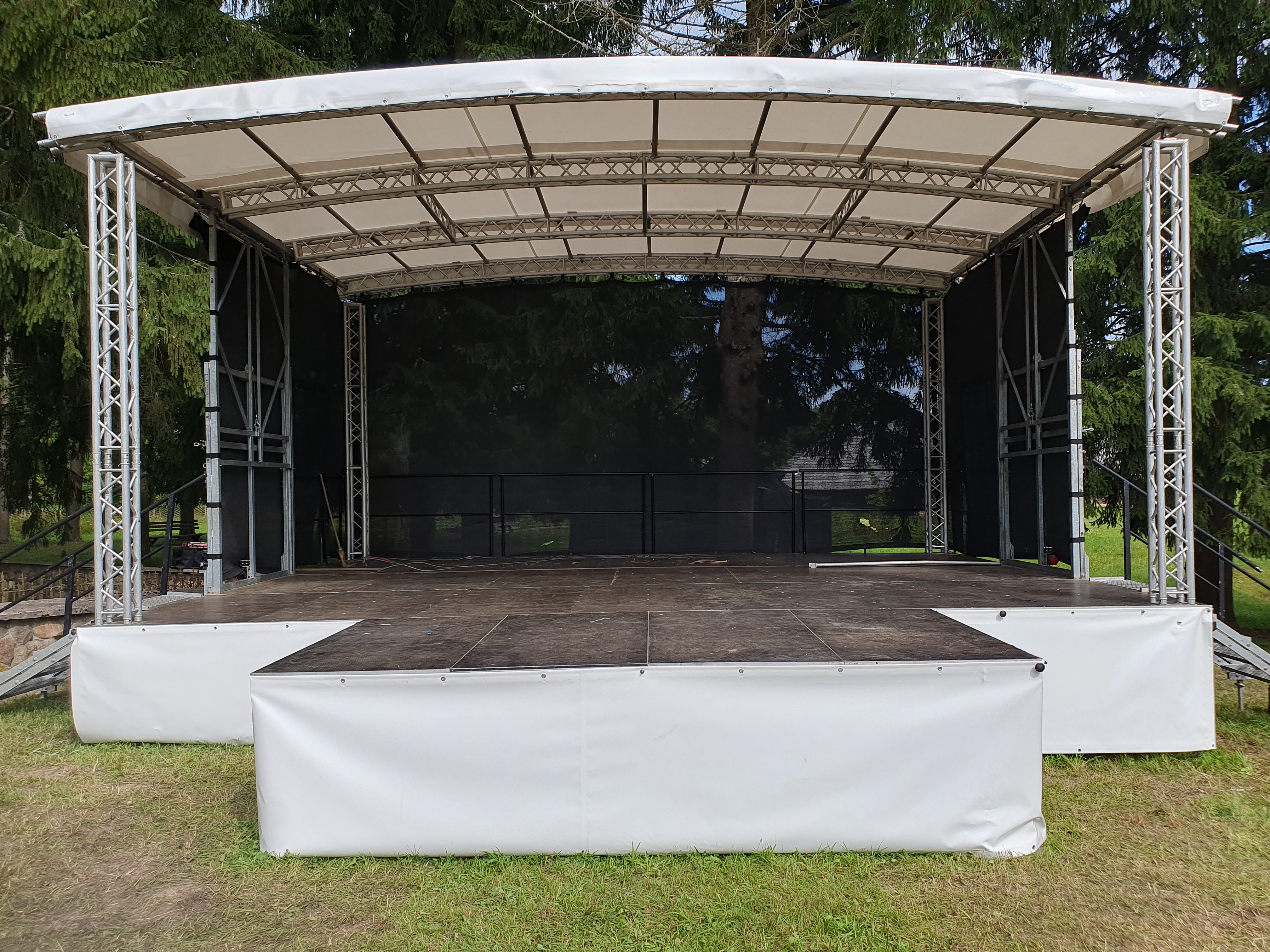 Scena su apšvietimu, choras scenoje ir žiūrovai renginio aikštėje